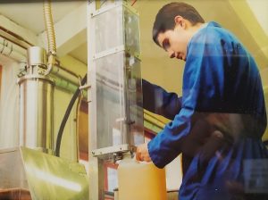 A coloured photograph of a male laboratory worker filling up a carton with chemicals. Photograph: Christeyns UK Ltd