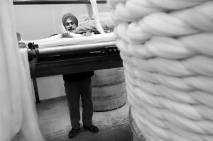 A black and white photograph of a Sikh employee working in the Combing Department of Haworth Scouring Company. Photograph: Tim Smith