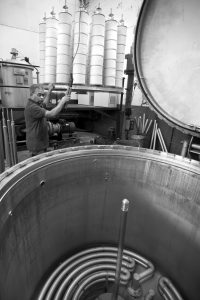 Photograph: Tim Smith | A black and white photograph of a man loading a dyeing vat with yarn at Bulmer & Lumb.