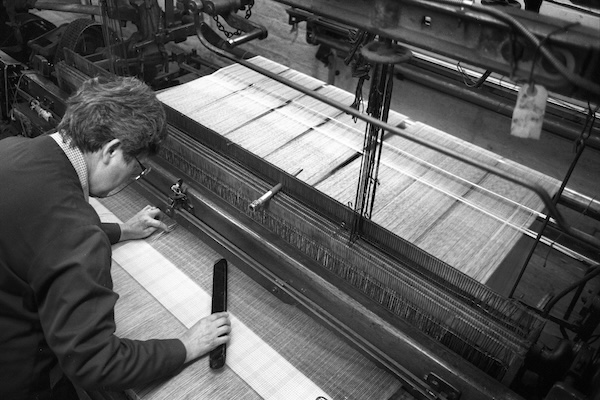 A pattern weaver, who produces the prototypes of new weaves, working on an old fashioned loom at Drummonds MIll. Photo by Tim Smith.