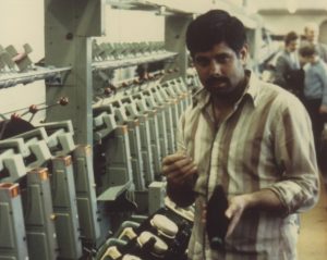 A coloured photograph of an asian male spinning worker at Salts Mill. Photograph: Bradford Museums & Galleries