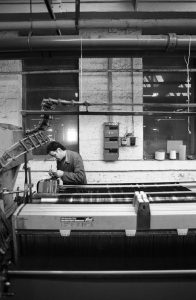 Black and white photograph of a male operative in the weaving department of Drummonds Mill. Photograph: Tim Smith.